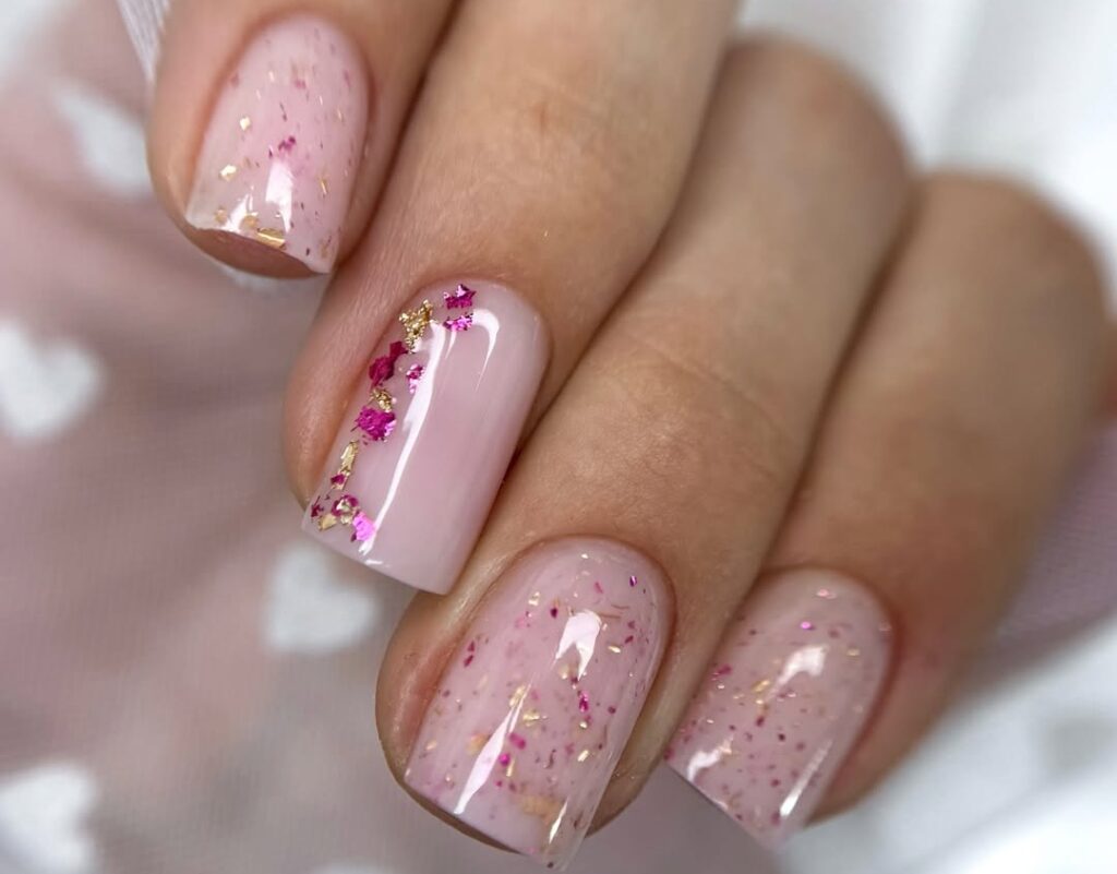 Paillettes et feuilles multicolores sur base nude - un nail art esthétique