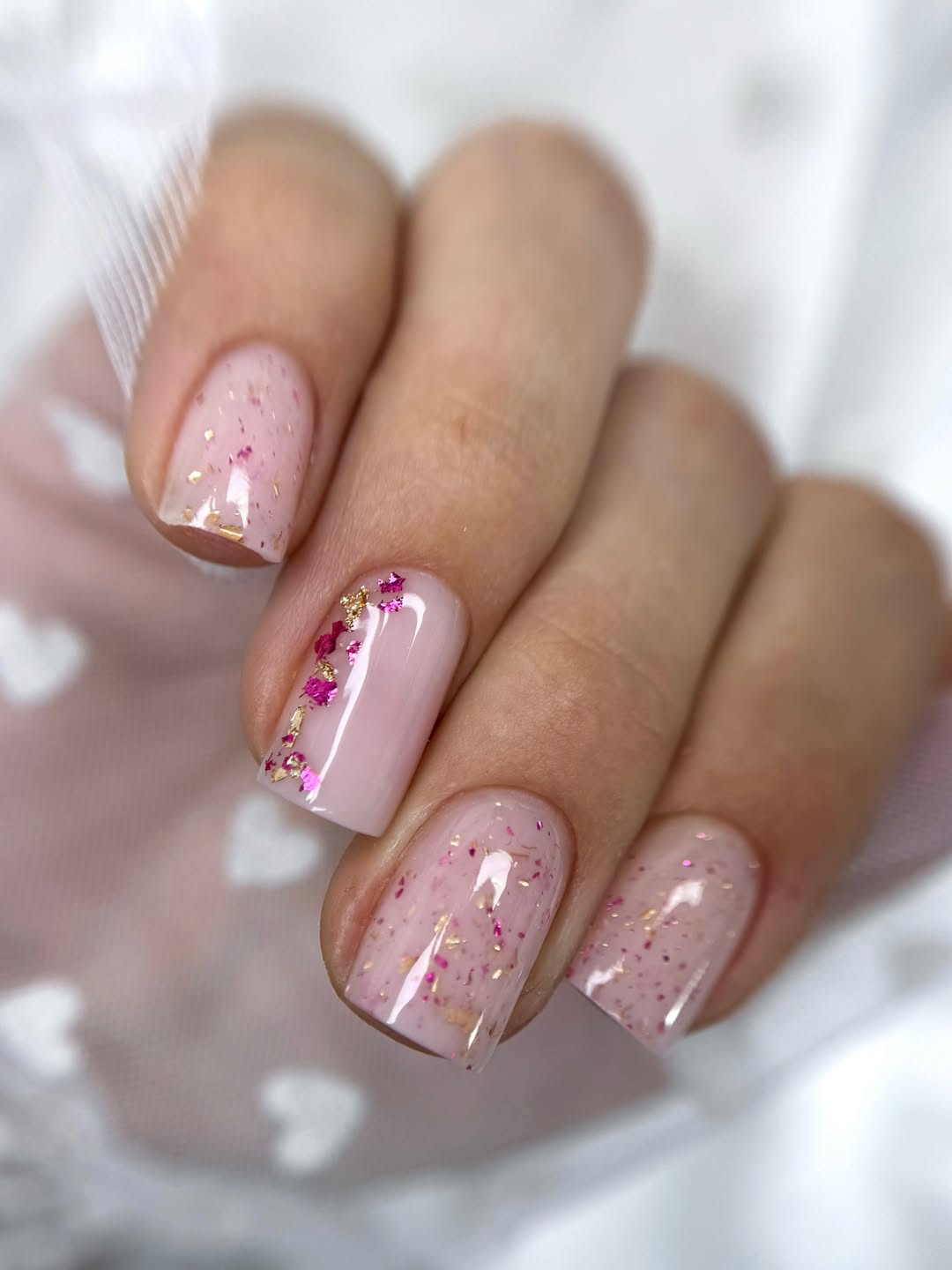 Paillettes et feuilles multicolores sur base nude - un nail art esthétique à tomber