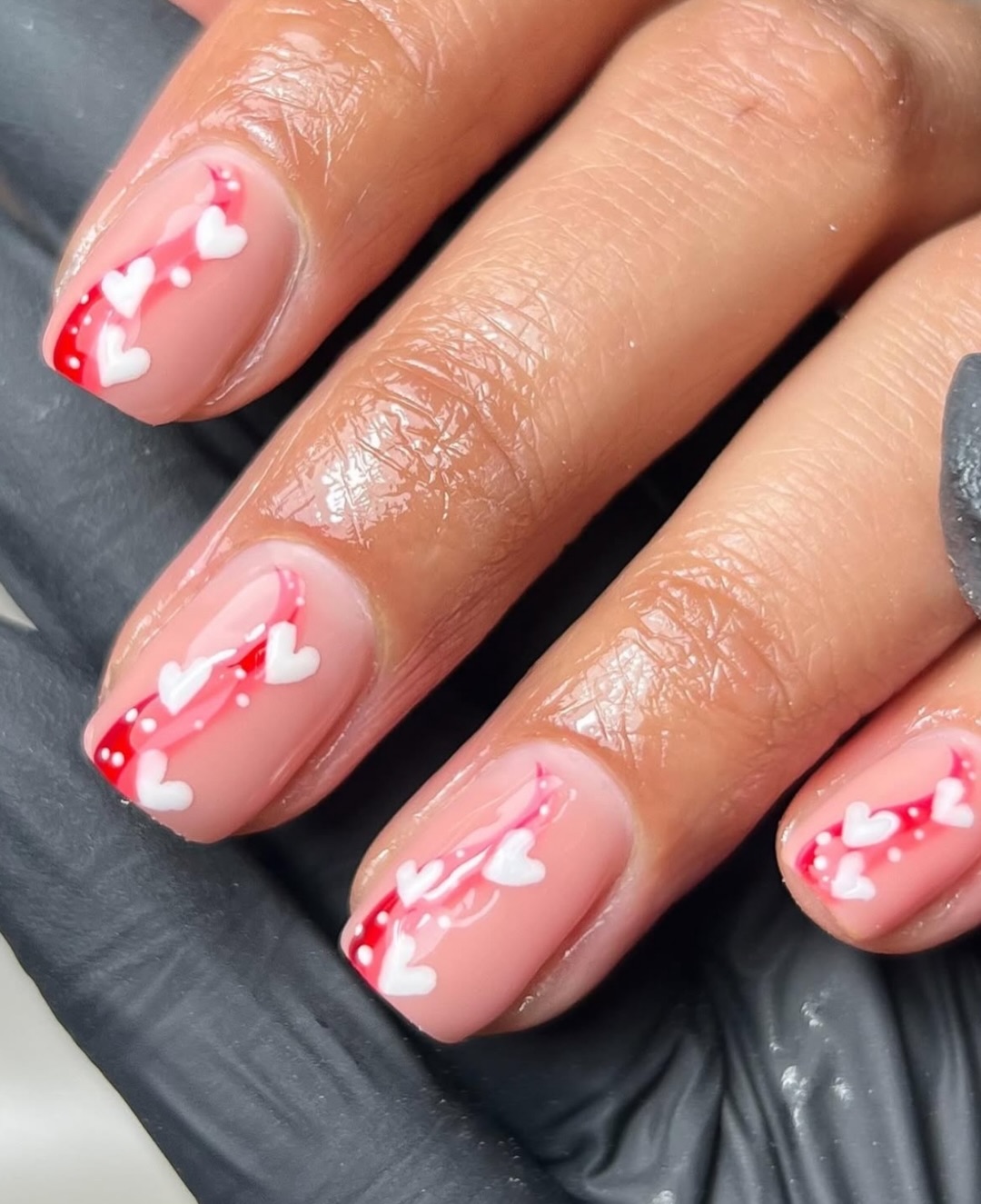 Manucure rose et rouge embellie de petits cœurs blancs