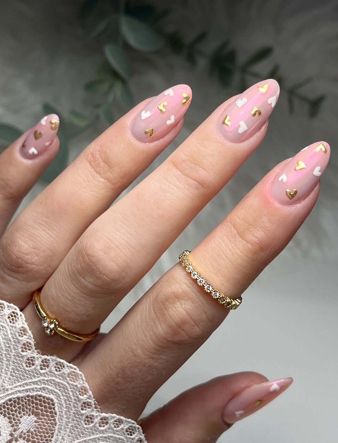 Une manucure féminine et raffinée ornée de petits cœurs blancs et dorés - un design chic et romantique