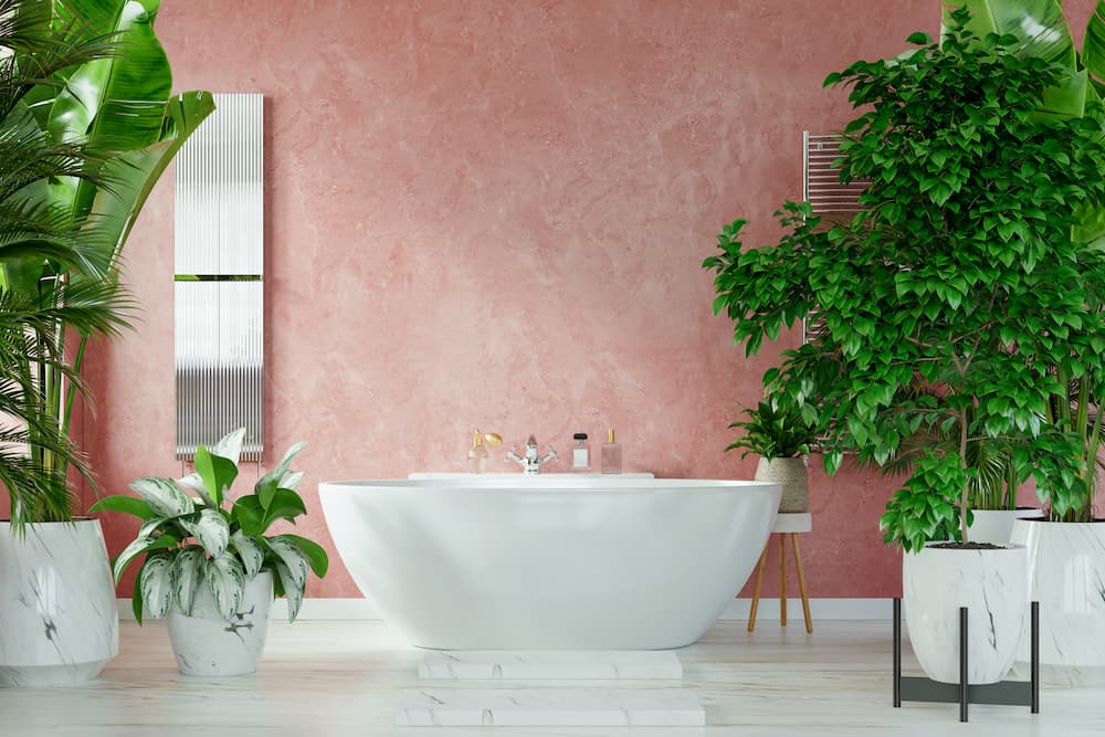 salle de bain murs rose poudré texturé baignoire blanche plantes luxuriantes ambiance apaisante