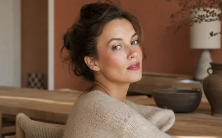 Femme arborant un maquillage été 2026 avec teint velouté, lèvres glossy framboise et paupière irisée argentée