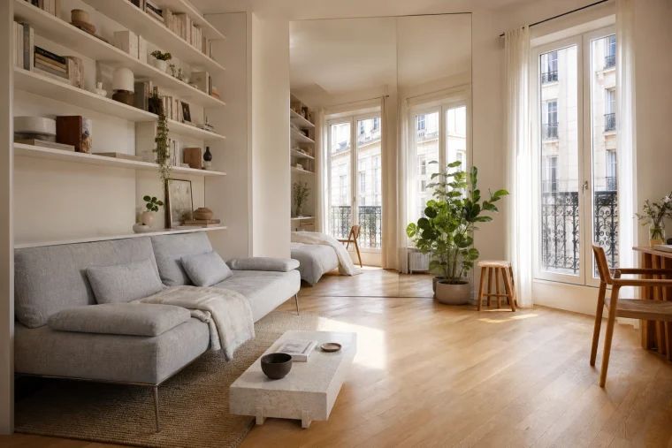 Studio parisien optimisé avec canapé-lit, miroir pleine hauteur et étagères jusqu'au plafond