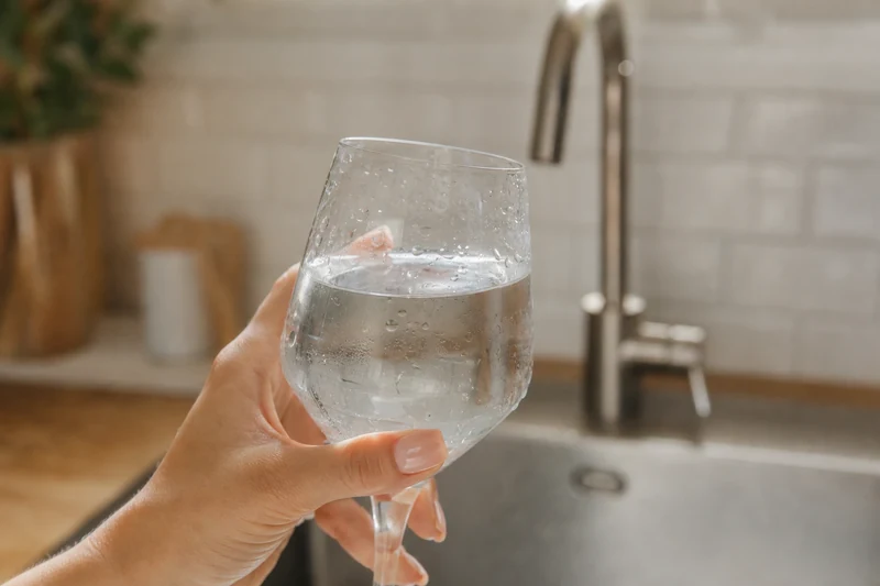 Verre d'eau du robinet rempli aux trois quarts dans une cuisine française lumineuse