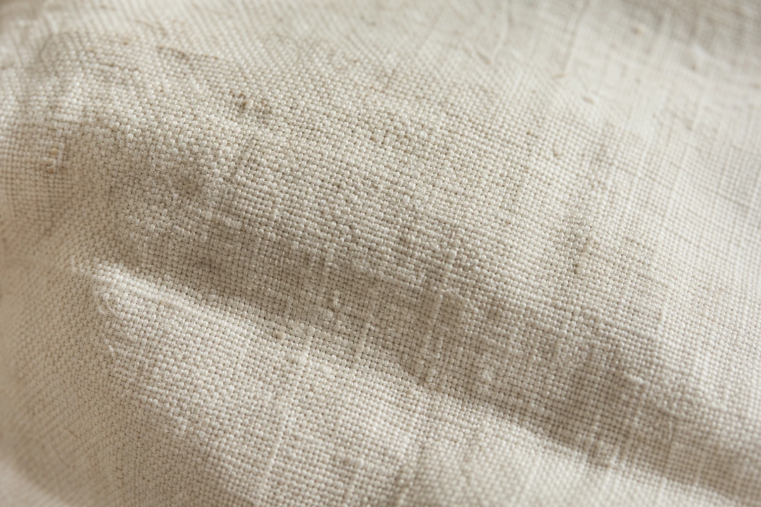Gros plan macro sur la trame d'un tissu en lin écru froissé révélant la fibre