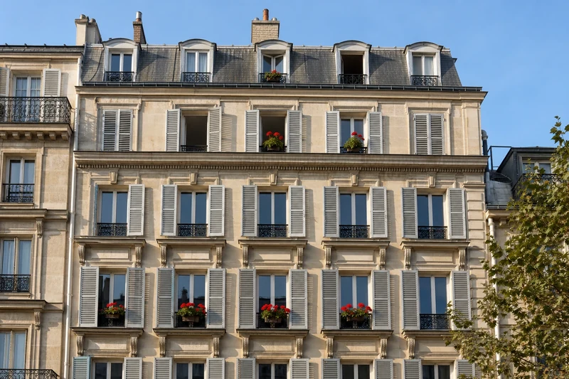Immeuble parisien avec volets clairs fermés en journée pour bloquer la chaleur