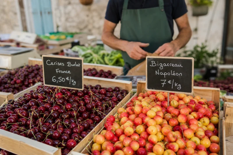 Étal de marché français en juin avec cerises Burlat et Bigarreau Napoléon en cagettes