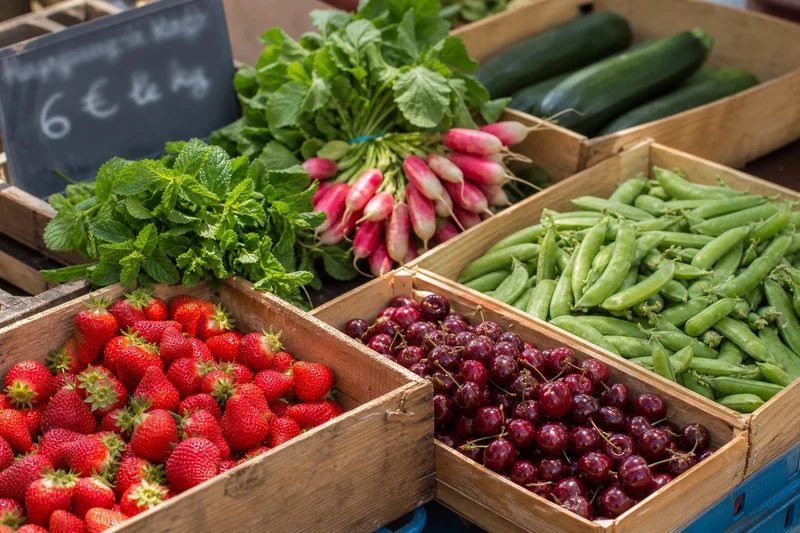 Étal de marché français en juin avec fraises, cerises, petits pois, radis et courgettes