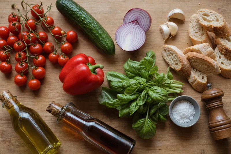 Ingrédients du gaspacho aux tomates cerises disposés à plat sur une planche en bois