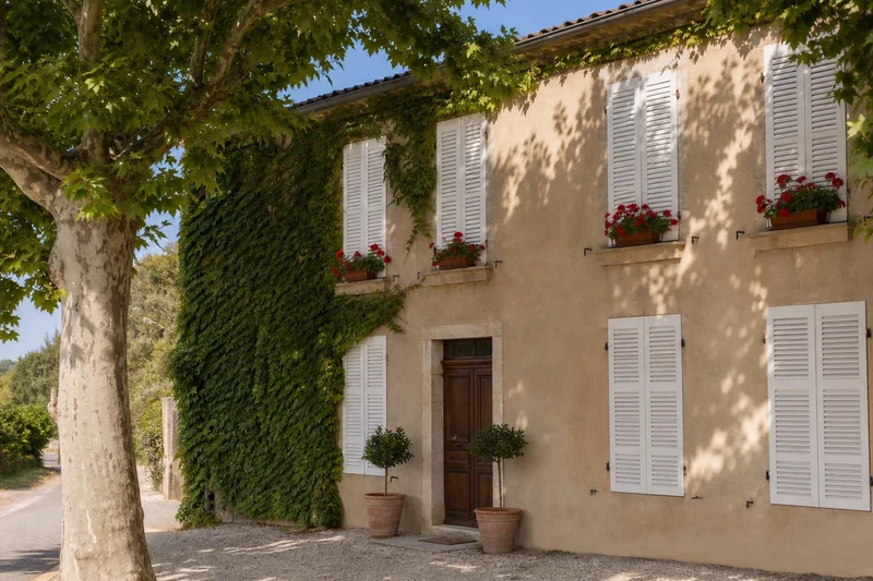 Façade de maison française aux volets fermés et arbre d'ombrage protégeant des rayons solaires