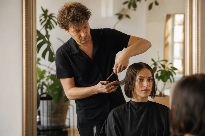 Coiffeur préparant la coupe d'un Japanese Bob, ciseaux et peigne en main