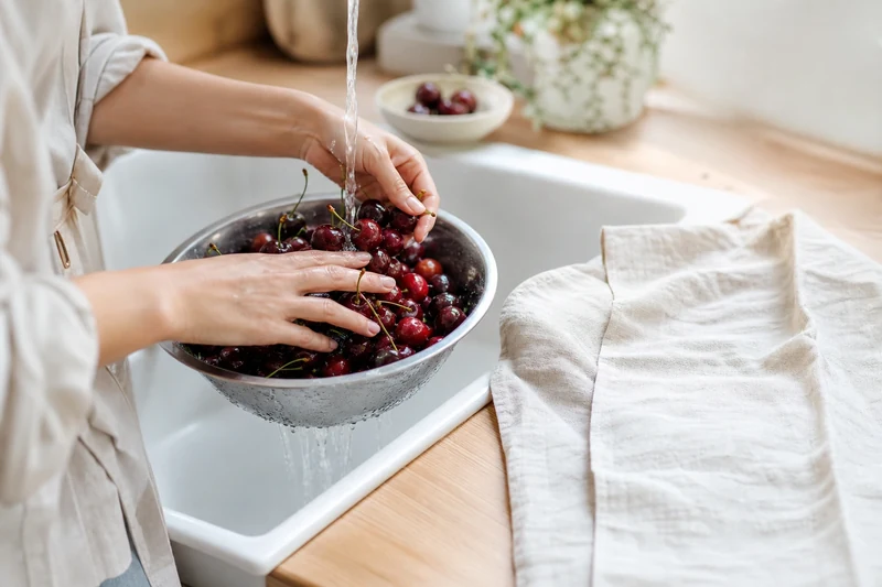 Rinçage délicat des cerises Burlat dans une passoire inox avant le séchage