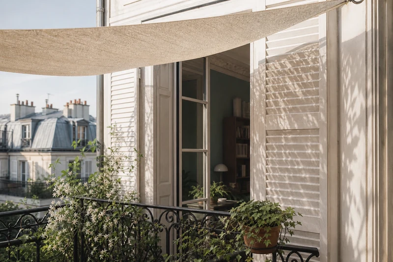 Balcon parisien équipé d'un voile d'ombrage beige et de plantes grimpantes