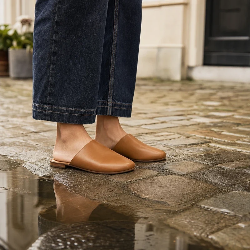 Mules cuir camel fermées sur pavés mouillés, ourlet de jean wide-leg brut