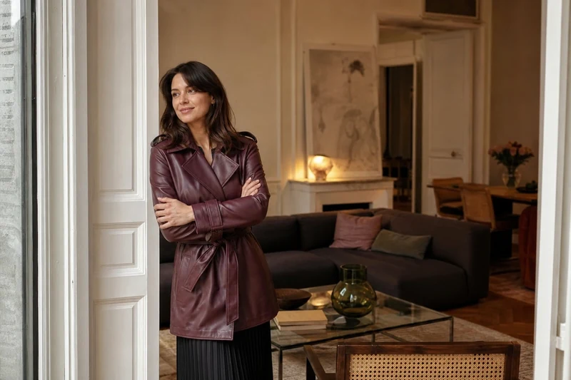 Trench cuir bordeaux, jupe midi plissée noire et bottines à talon