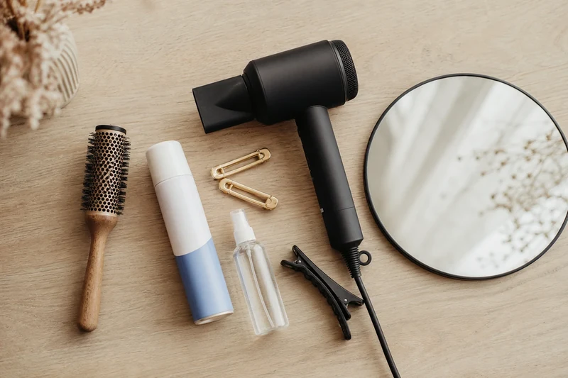 Matériel d'entretien d'une frange : brosse ronde, sèche-cheveux, shampoing sec, thermo-protecteur