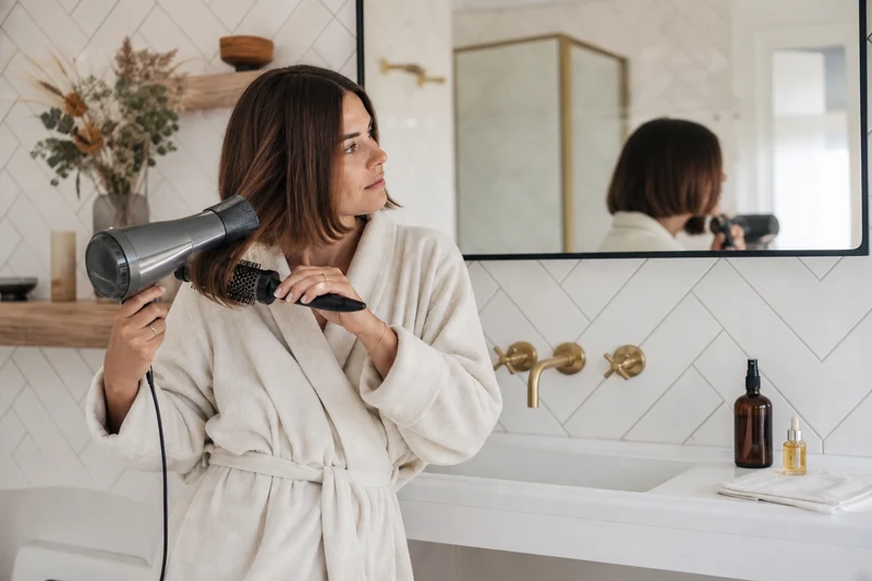 Femme brushant les pointes de son Japanese Bob à la brosse ronde à domicile