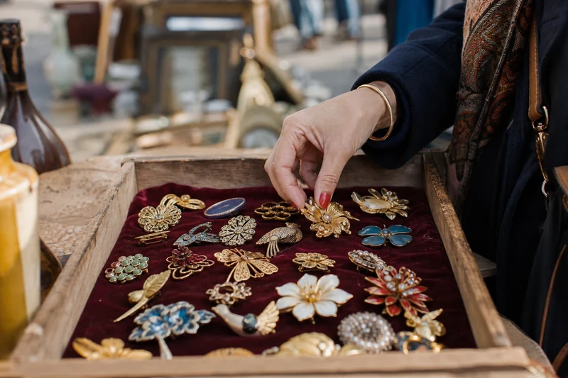 Caisse en bois remplie de broches vintage chinées aux Puces de Saint-Ouen