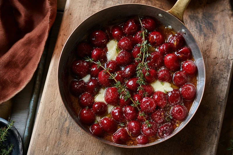 Cerises rôties au miel de fleurs et thym frais dans une poêle en cuivre