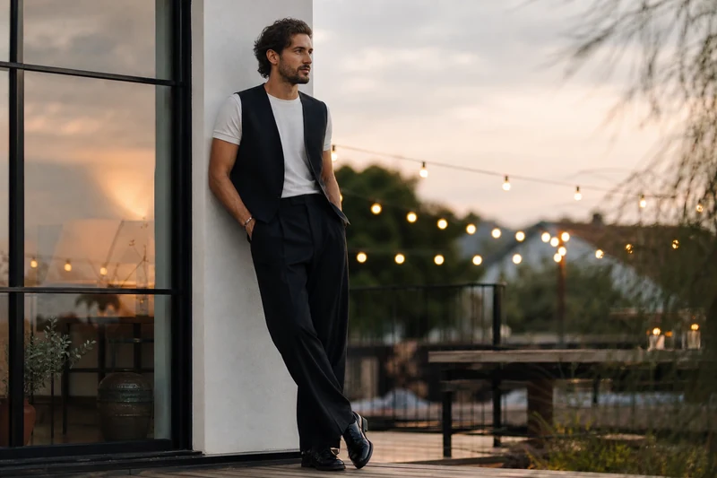 Homme en pantalon large noir, gilet de costume et derbies, look soirée été