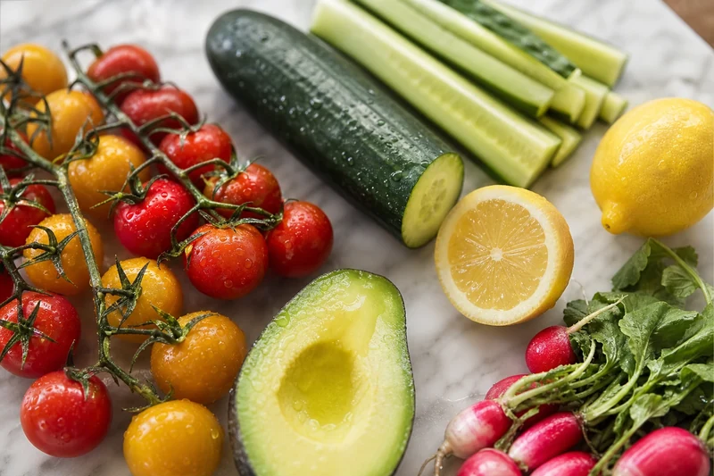 Ingrédients frais d'un plateau apéro sans cuisson : tomates cerises, concombre, radis, avocat et citron