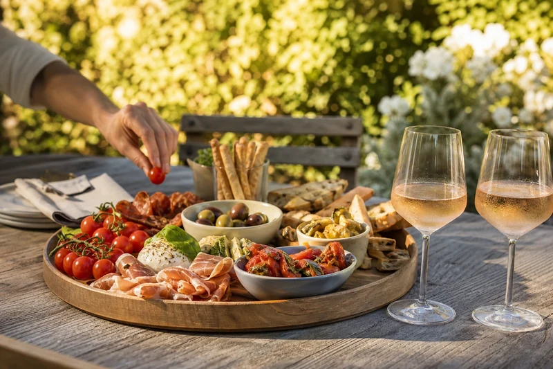 Plateau apéro sans cuisson servi à table de jardin avec deux verres de rosé frais