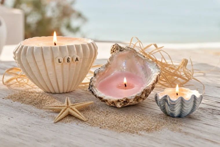 Trois bougies coquillages DIY allumées sur une table en bois avec perles-lettres formant un prénom