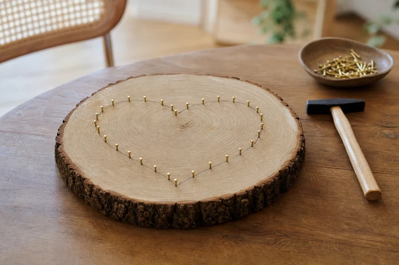 Rondelle de chêne avec contour de cœur en clous de tapissier dorés, étape du string art
