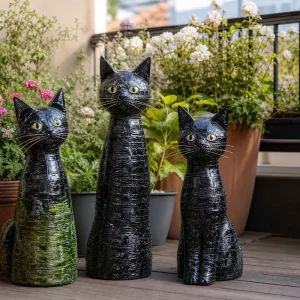 Trois chats décoratifs en bouteilles plastique recyclées ornant une terrasse fleurie