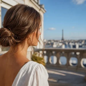 Femme en chignon flou bas dégageant la nuque par forte chaleur, robe en lin claire, terrasse parisienne