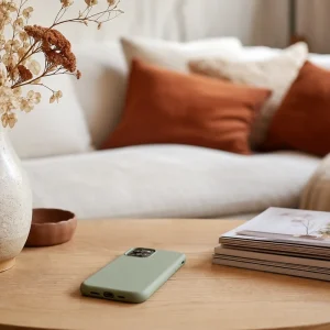 Coque de téléphone vert sauge posée sur la table basse au milieu de la déco