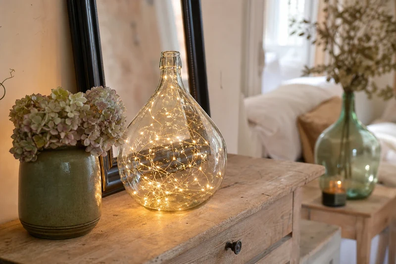 Insertion d'une guirlande LED fil de cuivre dans le goulot d'une dame-jeanne transparente