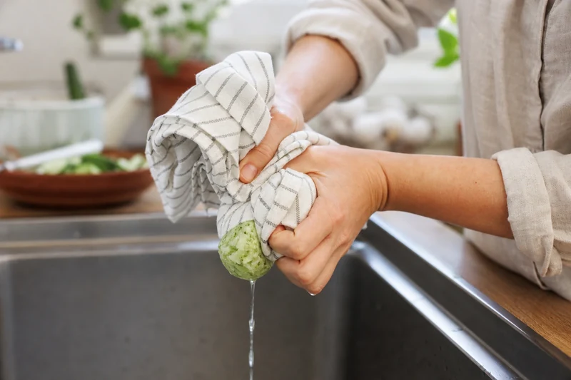 Pressage du concombre râpé dans un torchon propre pour extraire l'eau