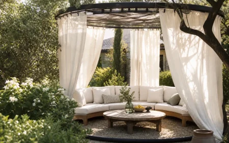 Cadre de trampoline recyclé en pergola ronde avec voilages en lin et coin salon dans un jardin français