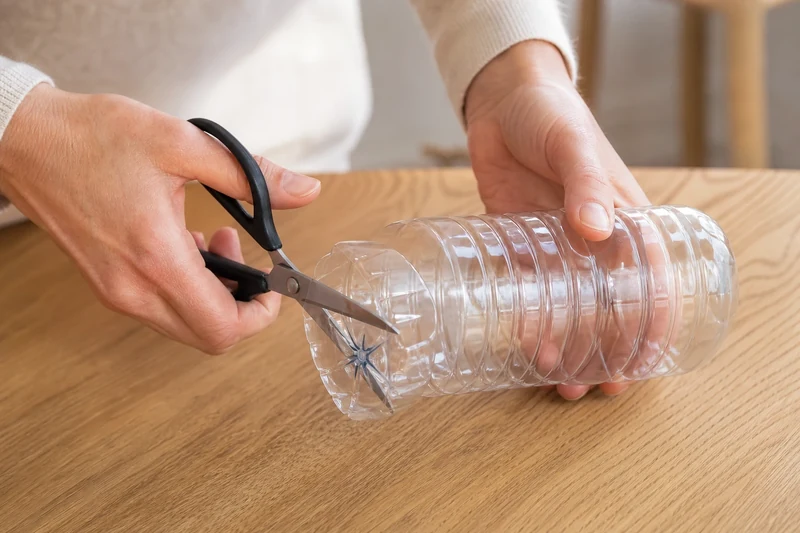 Découpe du fond de la bouteille en plastique aux ciseaux