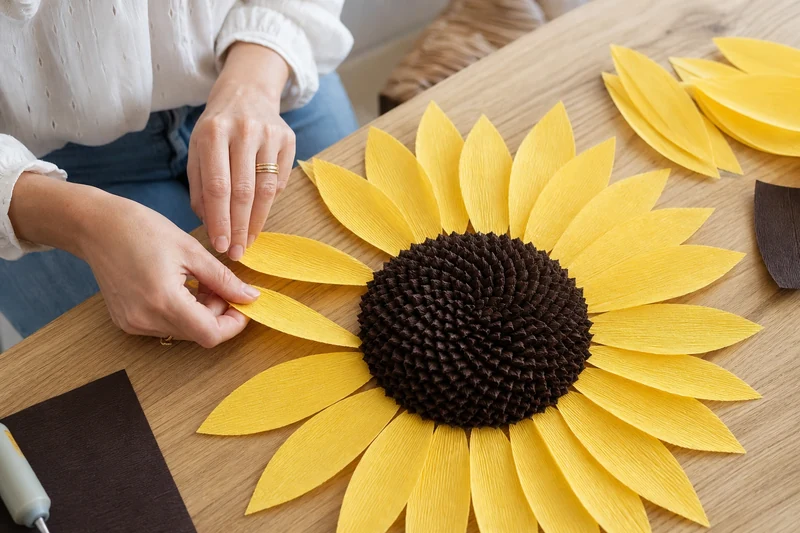 Collage des pétales jaunes en papier crépon autour du cœur marron du tournesol