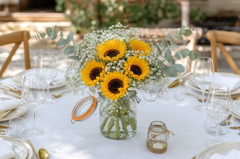 Grand bocal Le Parfait garni de tournesols courts, gypsophile et eucalyptus en centre de table