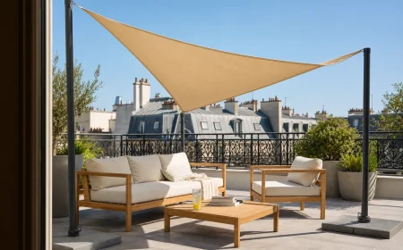 Voile d'ombrage triangulaire beige tendue sur trois mâts autoportants lestés au-dessus d'une terrasse française